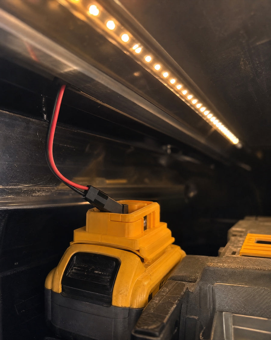 Battery adapter clipped to a 20V tool battery inside the truck cap